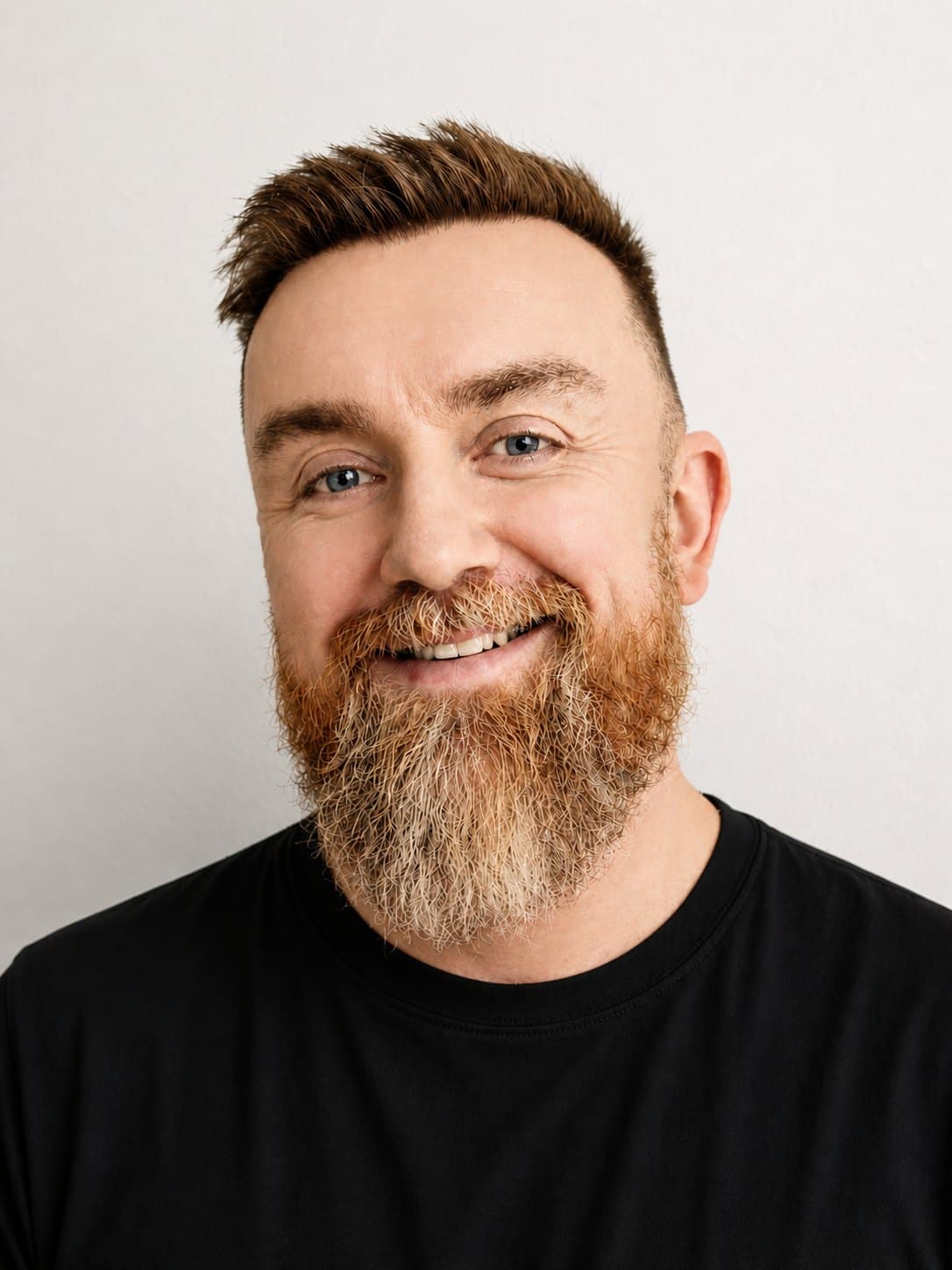 Norrie Hansen, smiling, in a black T-shirt against a white wall.